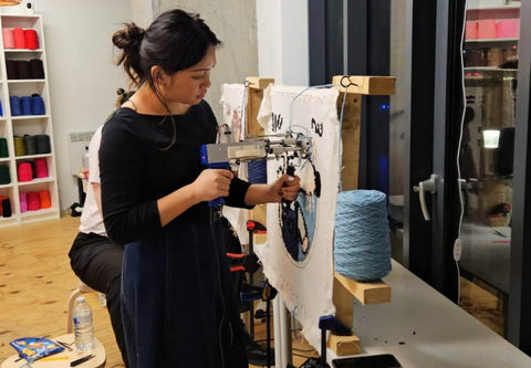 Beginner learning to use a tufting gun at a rug tufting workshop at Craft Studio London