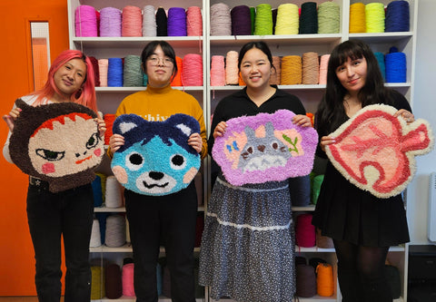Four happy people holding colourful handmade rugs at craft studio london