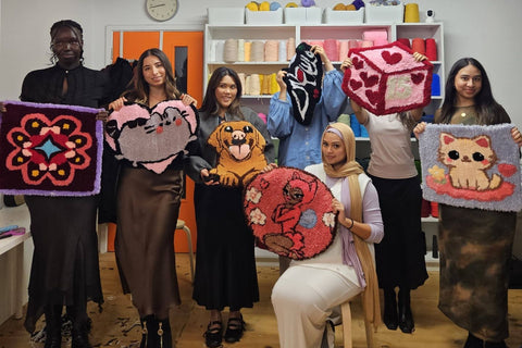Six guests proudly holding their colourful handmade tufted rugs at Craft Studio London rug tufting workshop