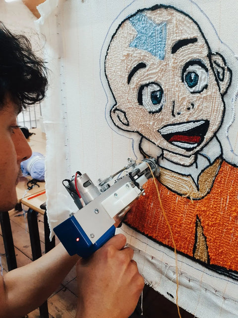 Person holding a tufting gun with a concentrated face, about to add more detail on the rug design of Avatar the last airbender
