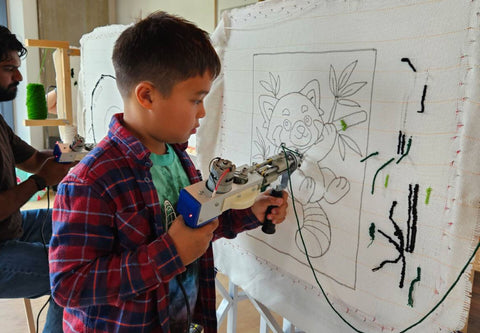 Child using a tufting gun on tufting frame with a red panda design in craft studio london